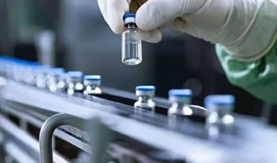 Supplied laboratory reference photograph showing a gloved hand inspecting a vial